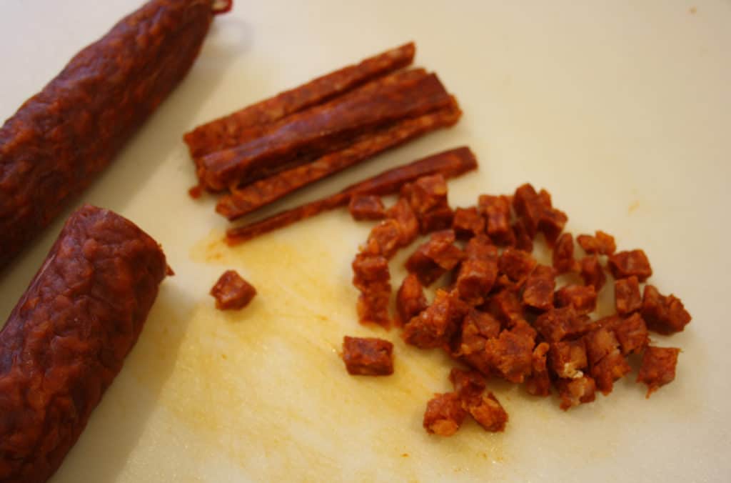 Piece of chorizo with some chopped in strips and some chopped finely
