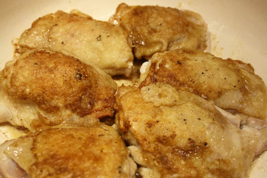 Chicken Thighs with browned skin uppermost in a frying pan