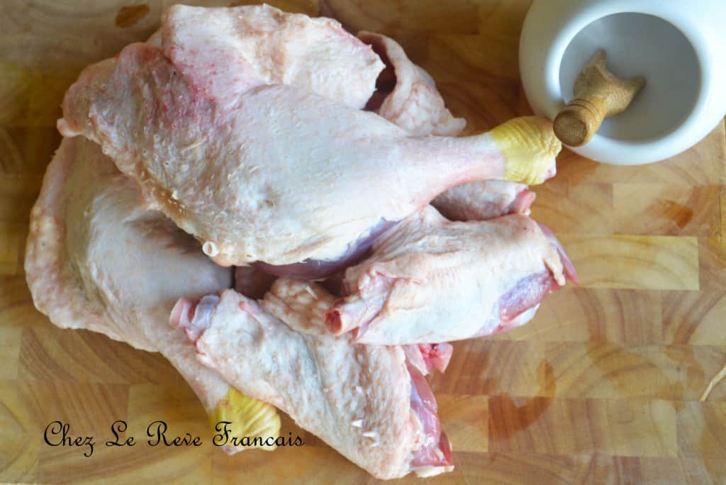 Pile of raw duck legs and a pot of salt.
