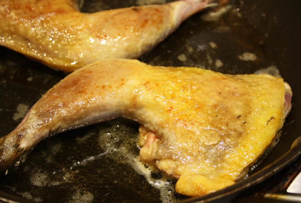 legs frying in butter in a frying pan until golden.