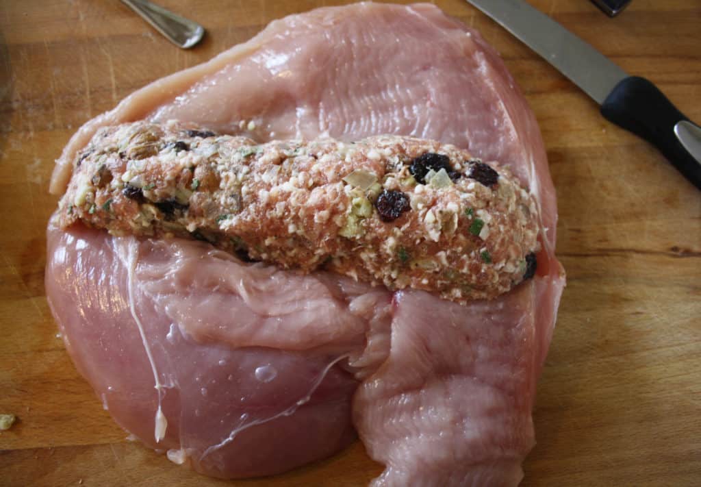 opened out turkey breast with stuffing in a log in the middle.