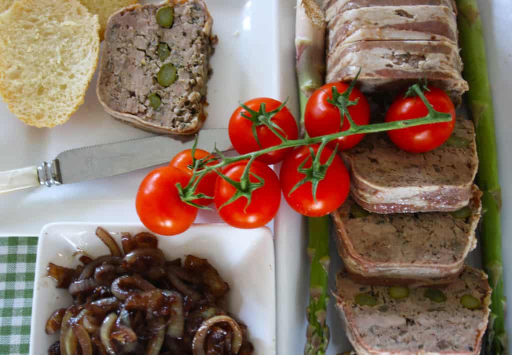 slices of terrine with bread, chutney and tomatoes.