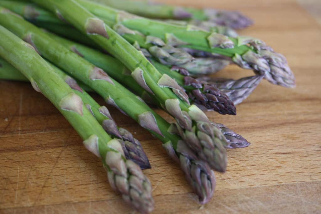 fresh asparagus spears on a chopping board.