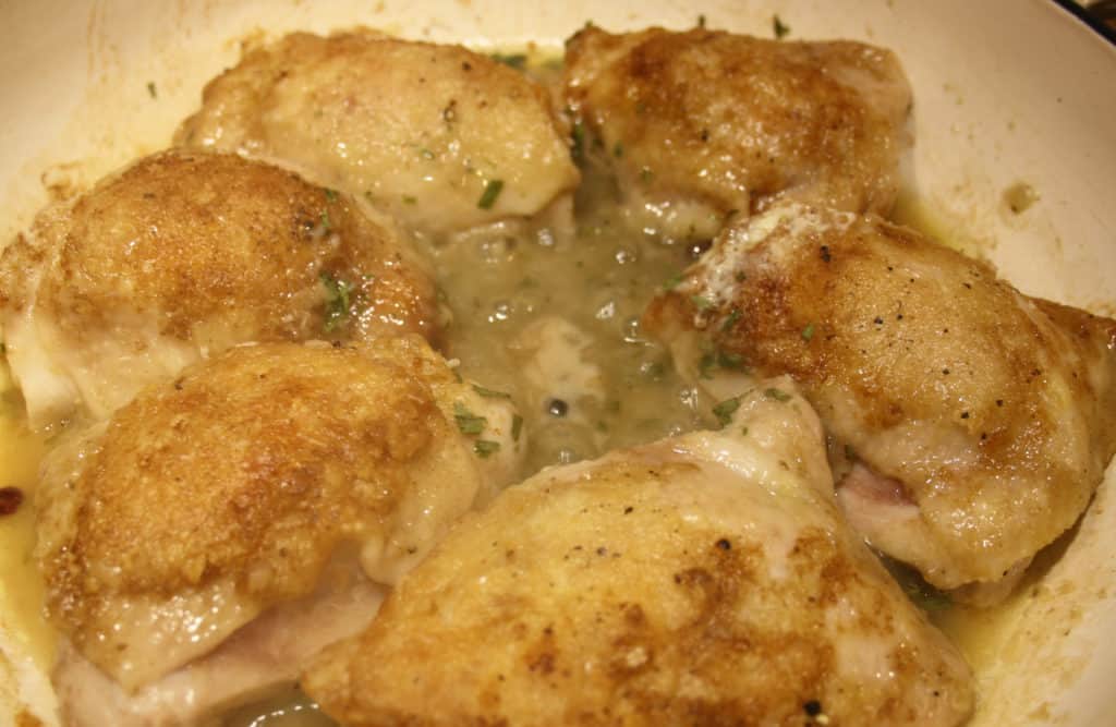 Chicken Thighs with stock added to a drying pan.