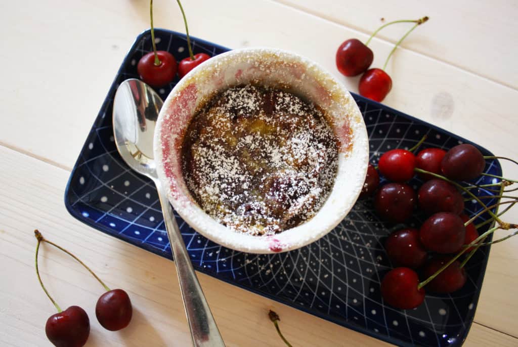 dessert served on a plate, surrounded by cherries.