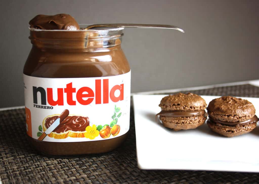 jar of nutella and two macarons on a plate