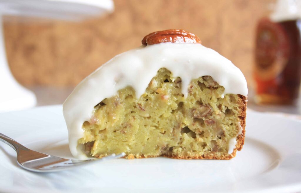 Slice ofPecan Banana Avocado Cake covered with icing. 