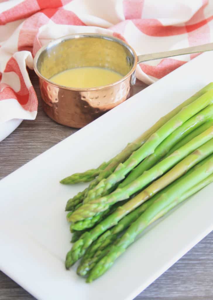 plate of asparagus and pot of easy hollandaise sauce to the side.