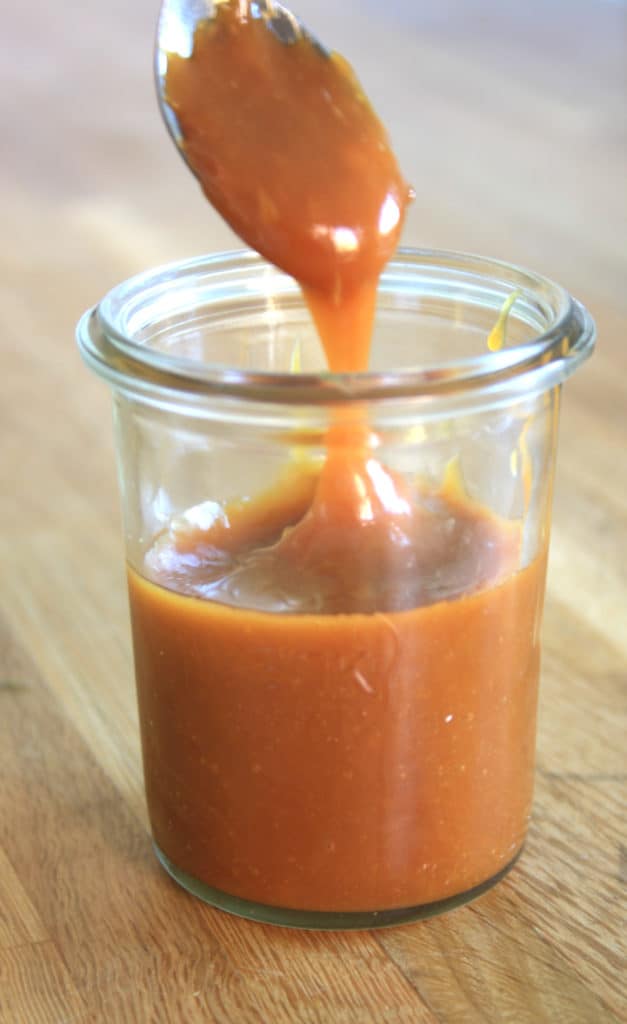glass jar of salted caramel with a spoonful of sauce. 