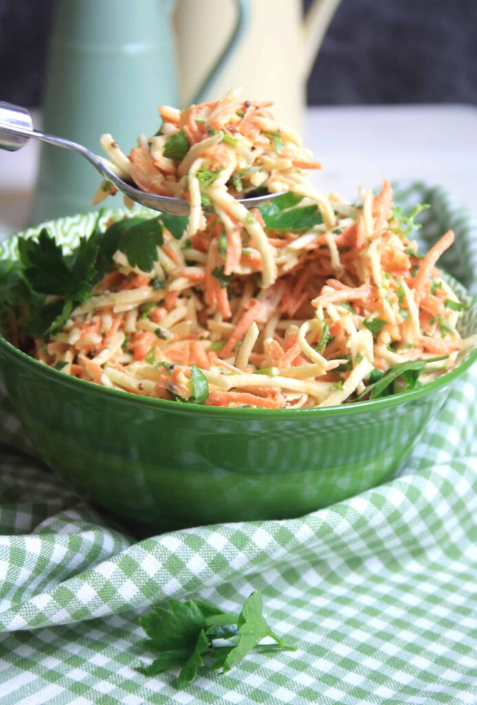 ciotola verde piena di carota e sedano rapa remoulade con un cucchiaio