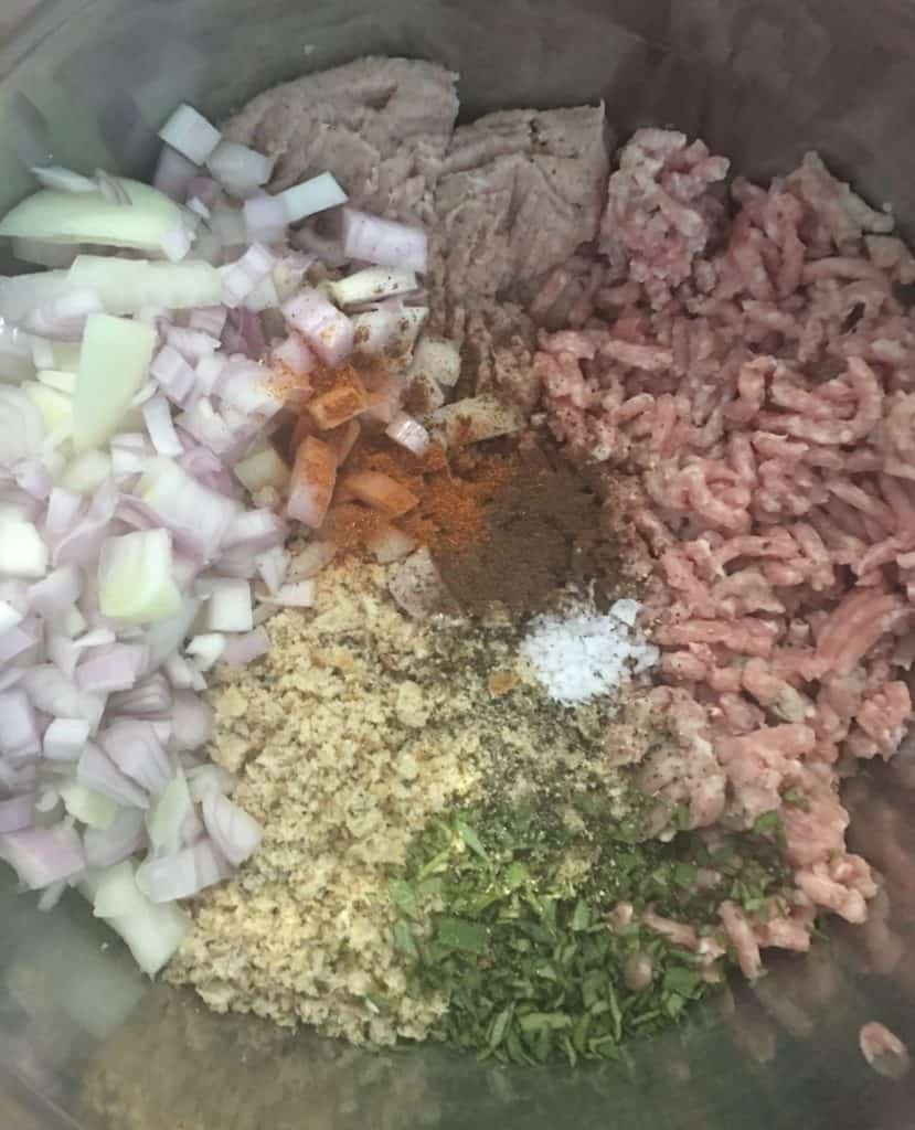 Bowl full of ingredients including pork, onions breadcrunbs and spices