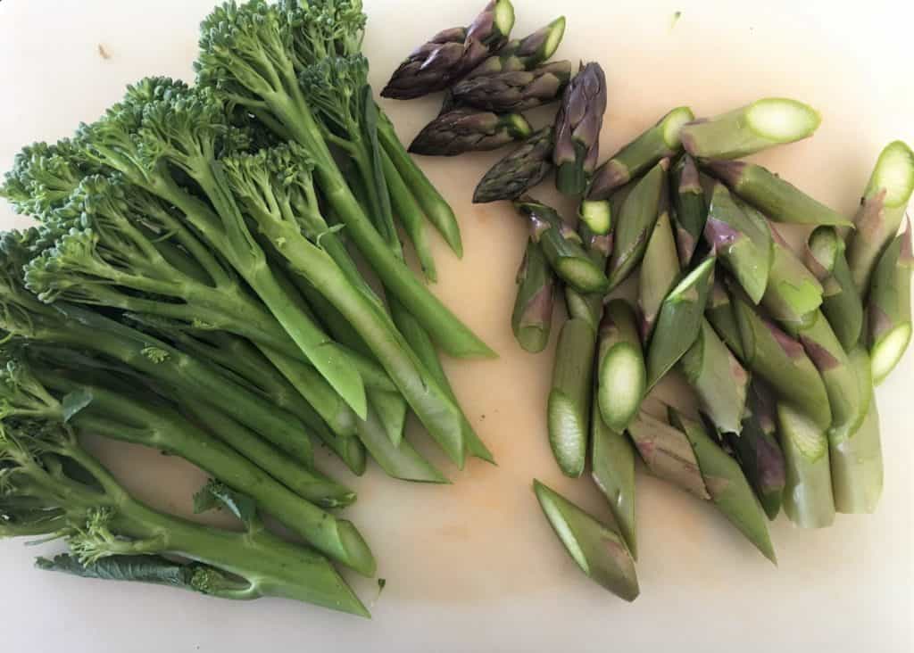 prepared broccoli and asparagus on a board.