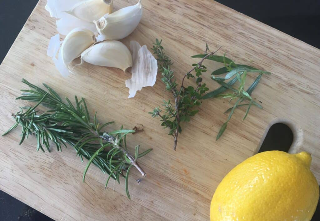 lemon, garlic and herbs on a board