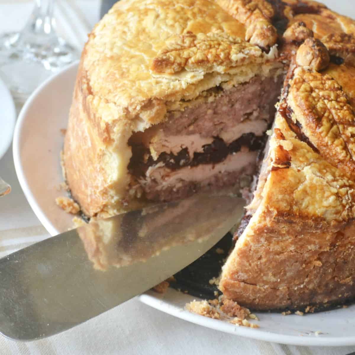 raised turkey and cranberry pork pie with slice cut out.