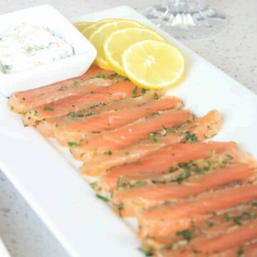 sliced cured salmon on a plate with lemon