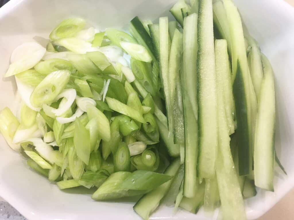 sliced spring onions and cucumber in a bowl