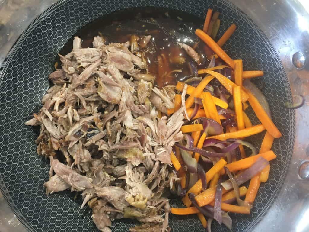 shredded duck and carrots and onions in a wok