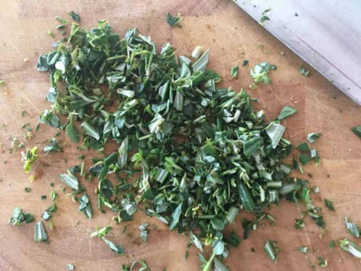 chopped thyme and rosemary on a wooden chopping board