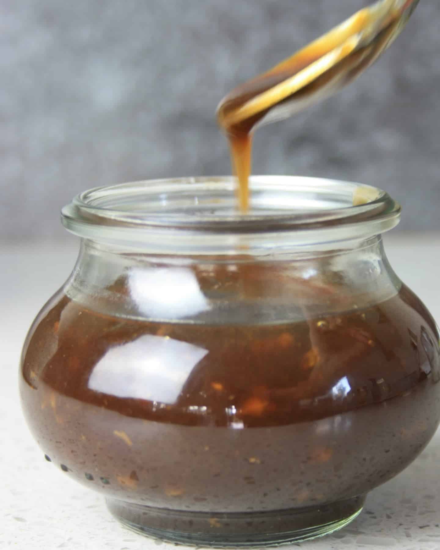 sauce dribbling of a spoon into a glass jar