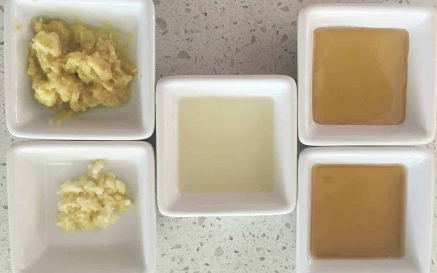 5 square bowls with ingredients such as oil, garlic and ginger