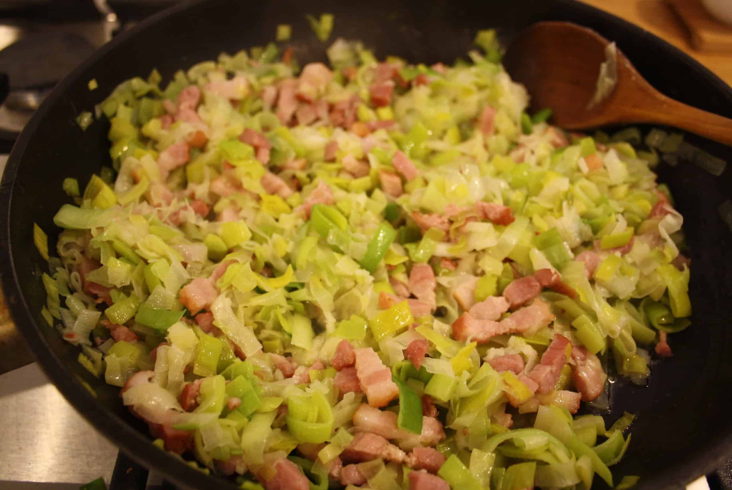 chopped leeks and bacon in a frying pan.