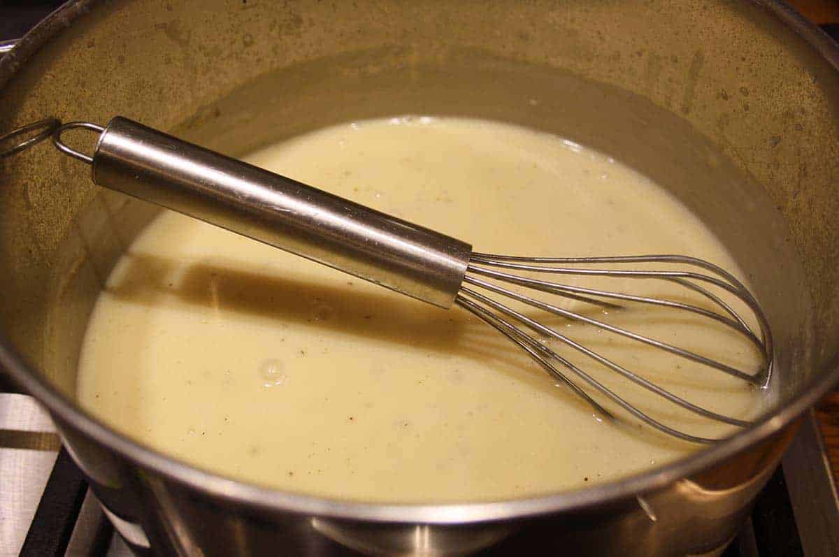 sauce in a pan with a whisk.