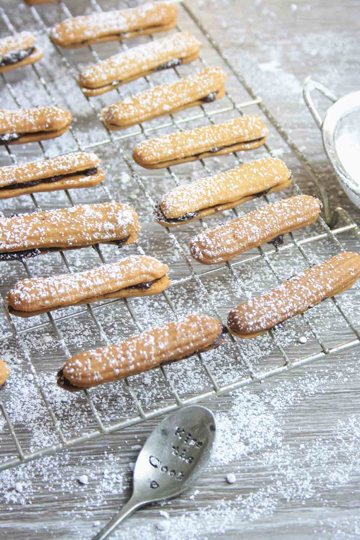 sandwich biscuits on a rack sprinkled with icing sugar.