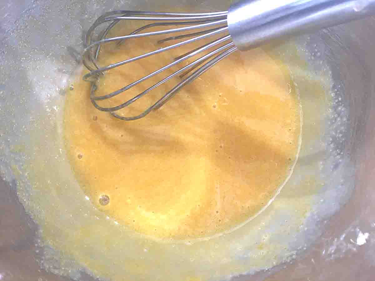 eggs and sugar whisked together in a metal bowl.
