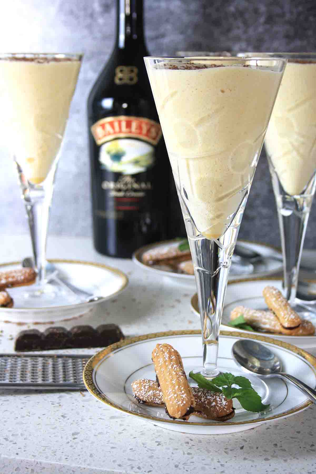 three glasses of dessert with Baileys liqueur bottle in background