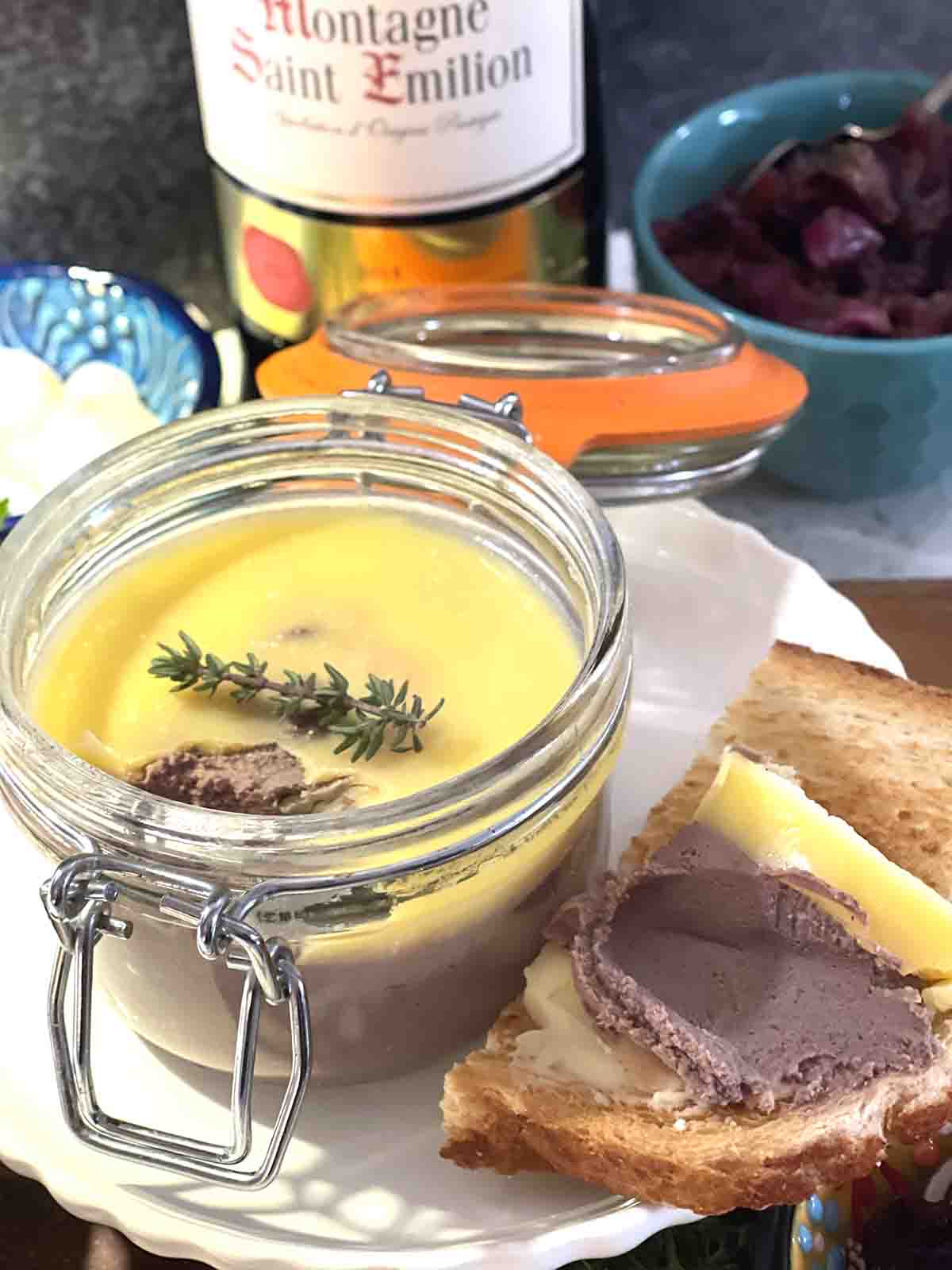 chicken liver parfait in a pot surrounded with bread, wine and chutney.