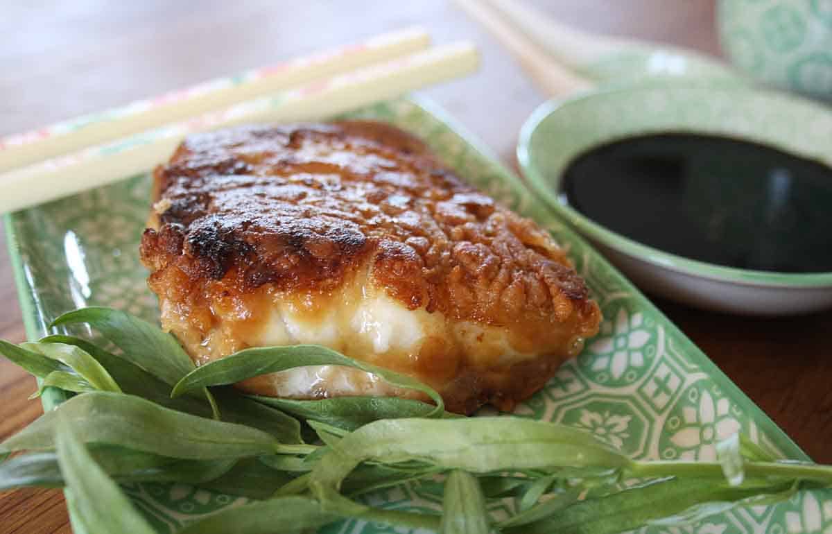 crispy miso cod on a plate with a dipping sauce in a pot.