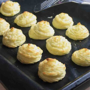 piped swirls of potato on a baking tray.