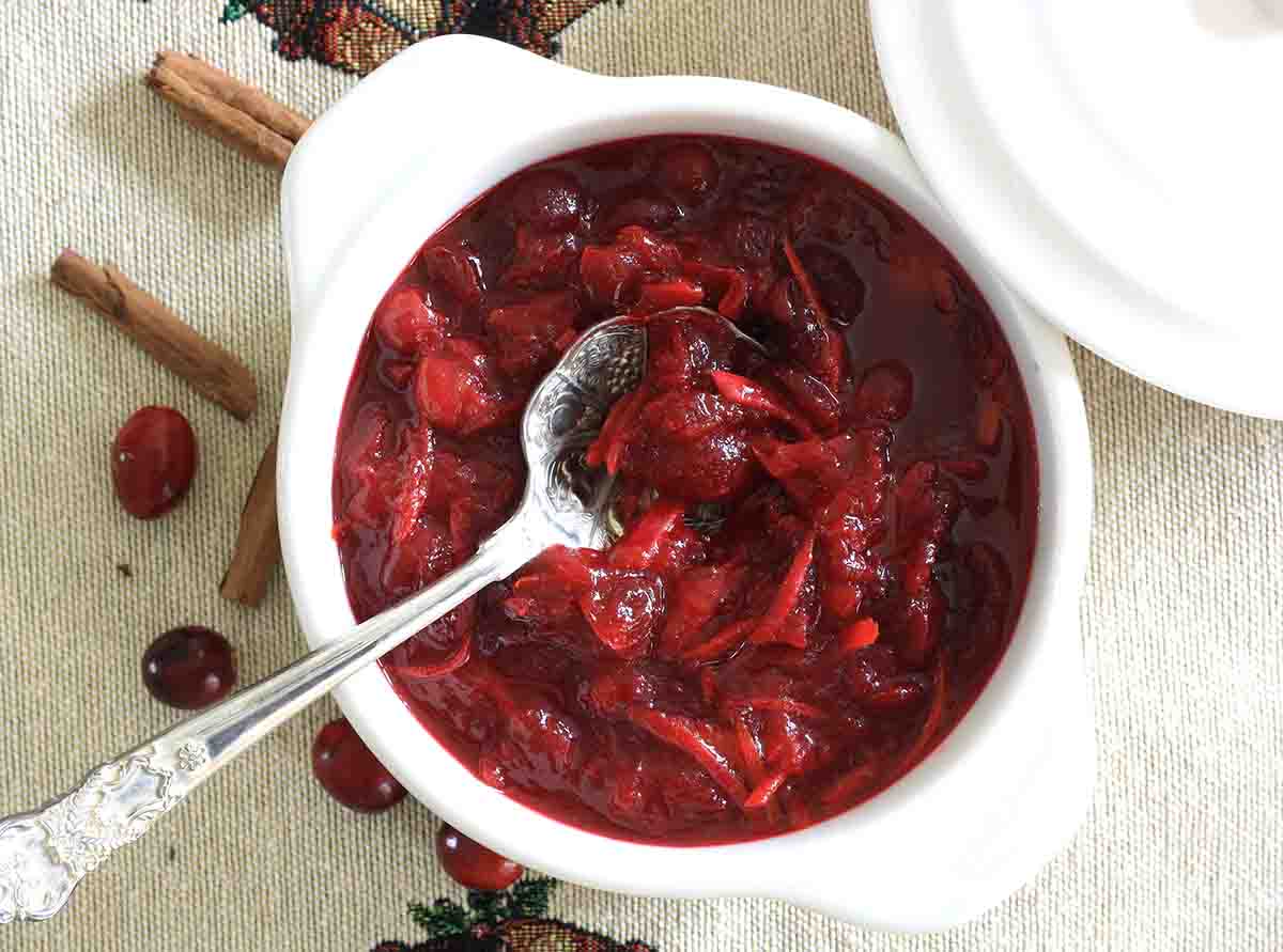 overhead shot of a bowl of cranberry sauce with a spoon in it.
