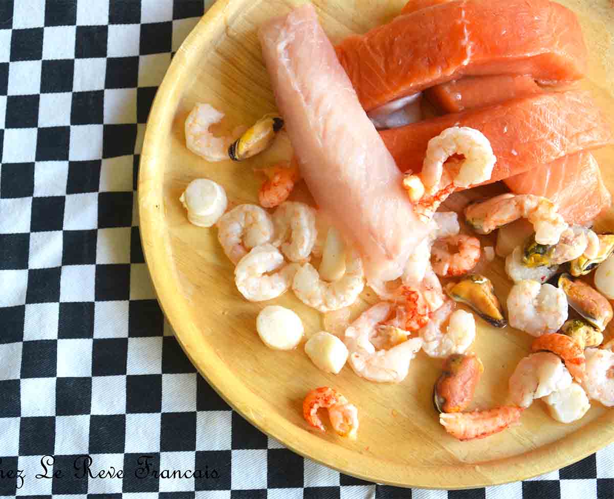 check cloth with a wooden board piles with fish fillets, prawns and mussels.