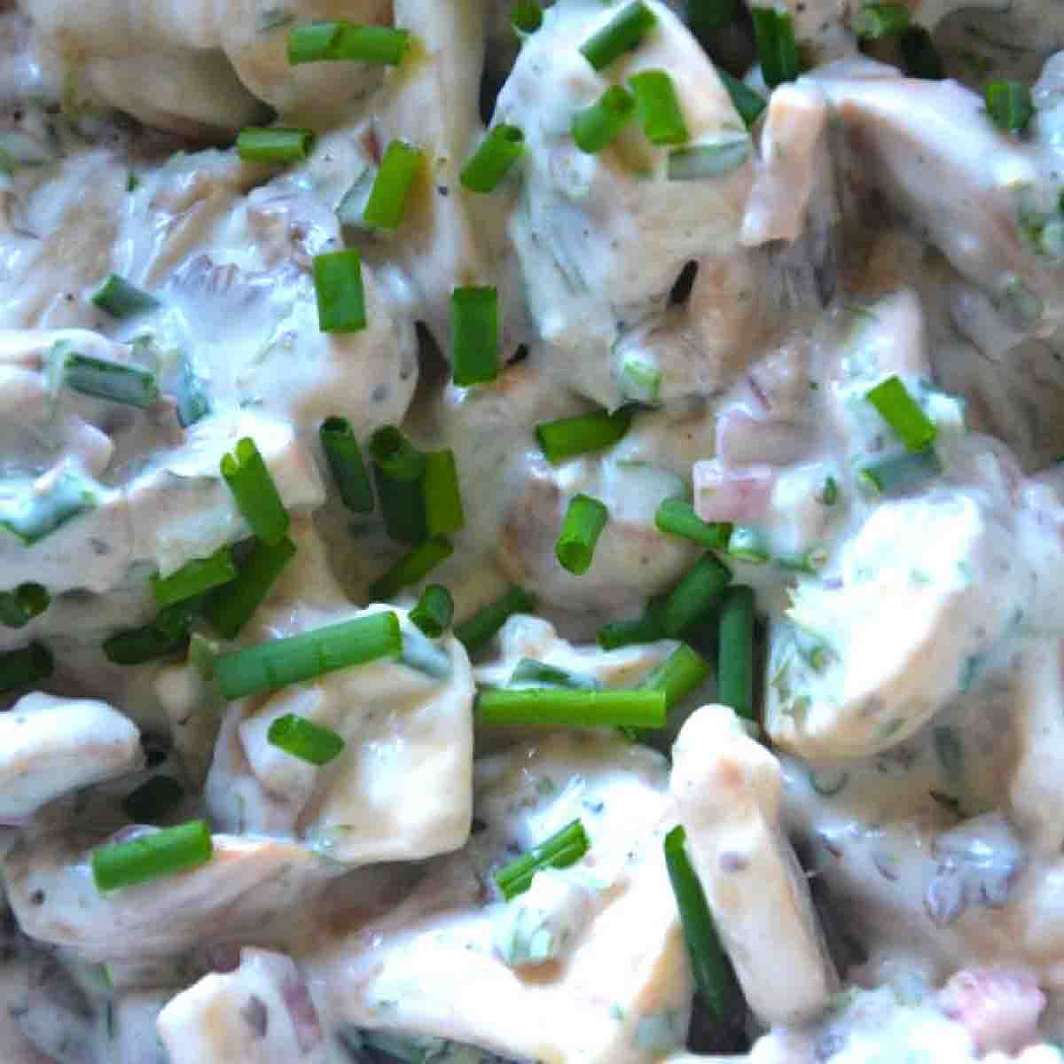 close up of marinated mushroom salad, garnished with chives.