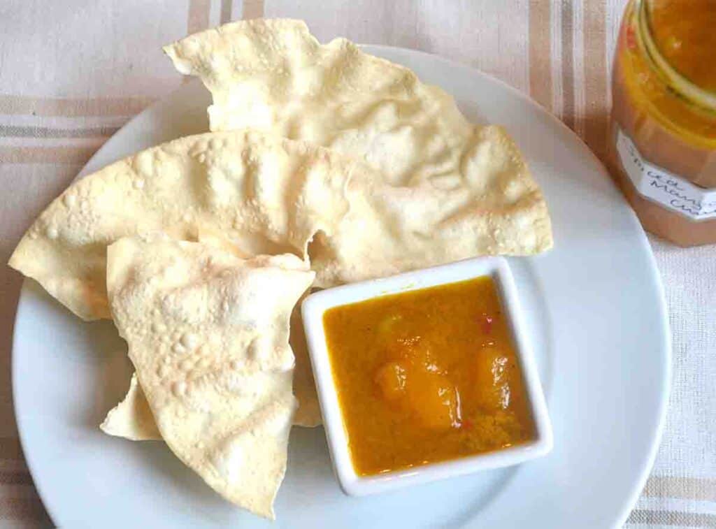 poppadums om a plate with small pot of spicy mango chutney with lime.