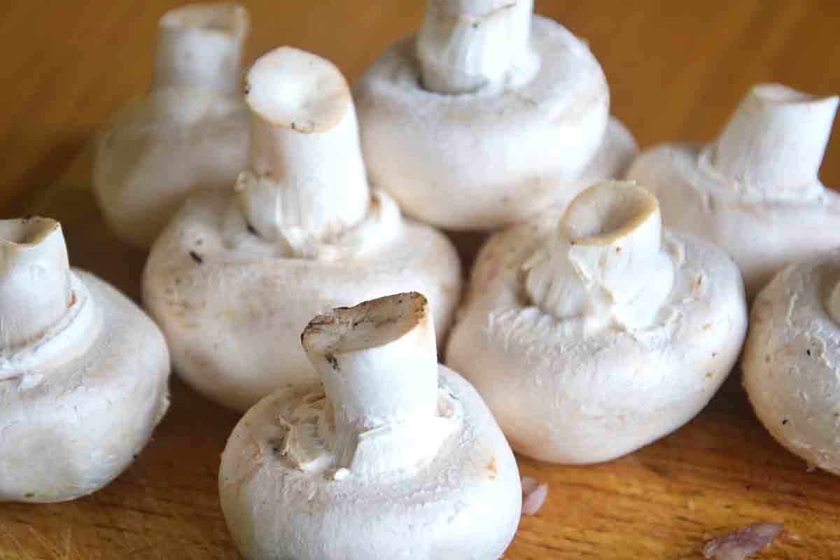 close up of white mushrooms on a board.