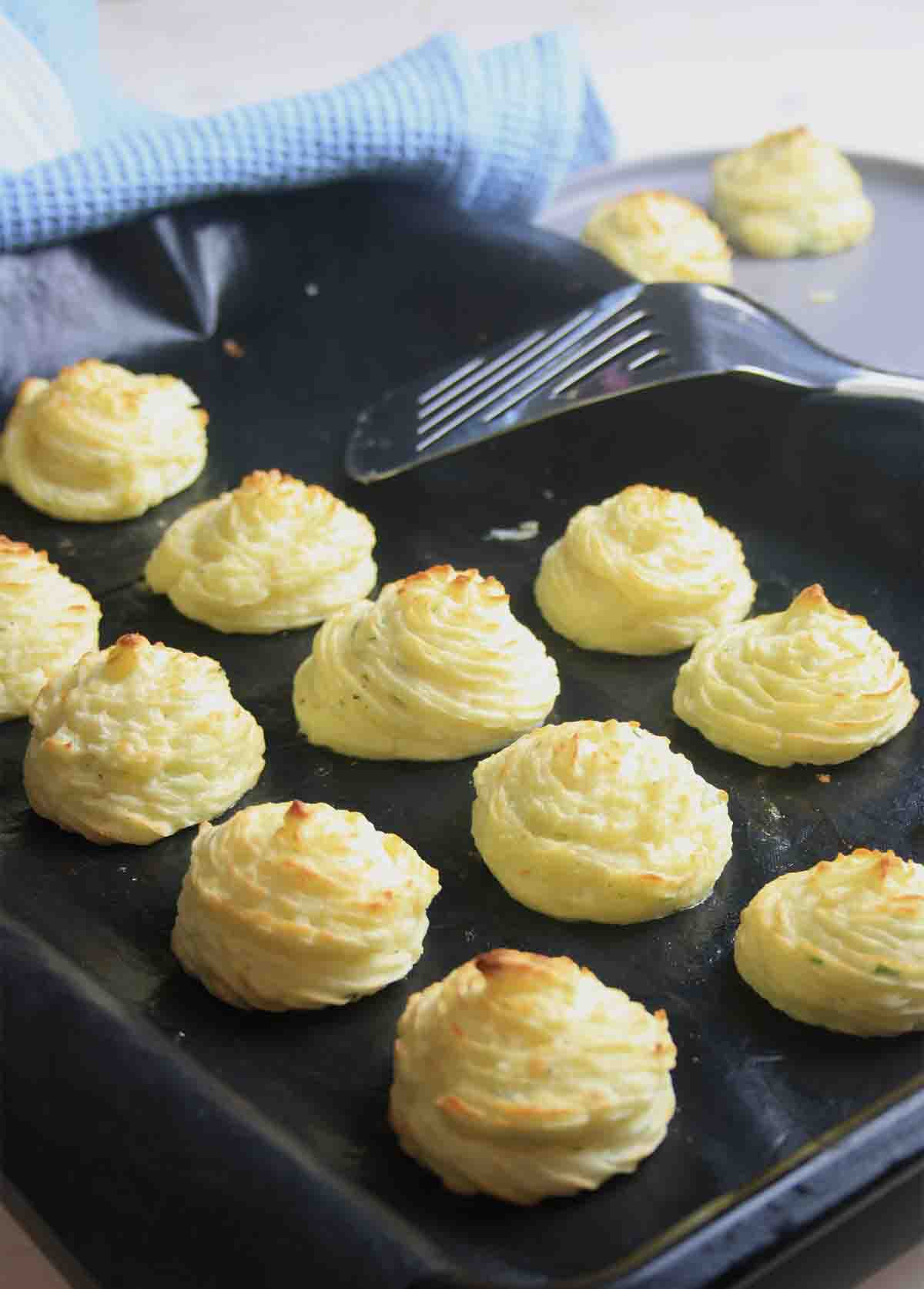 oven tray with rows of piped duchess potatoes.