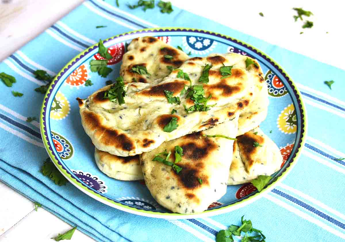 pile of homemade naan breads on a plate.