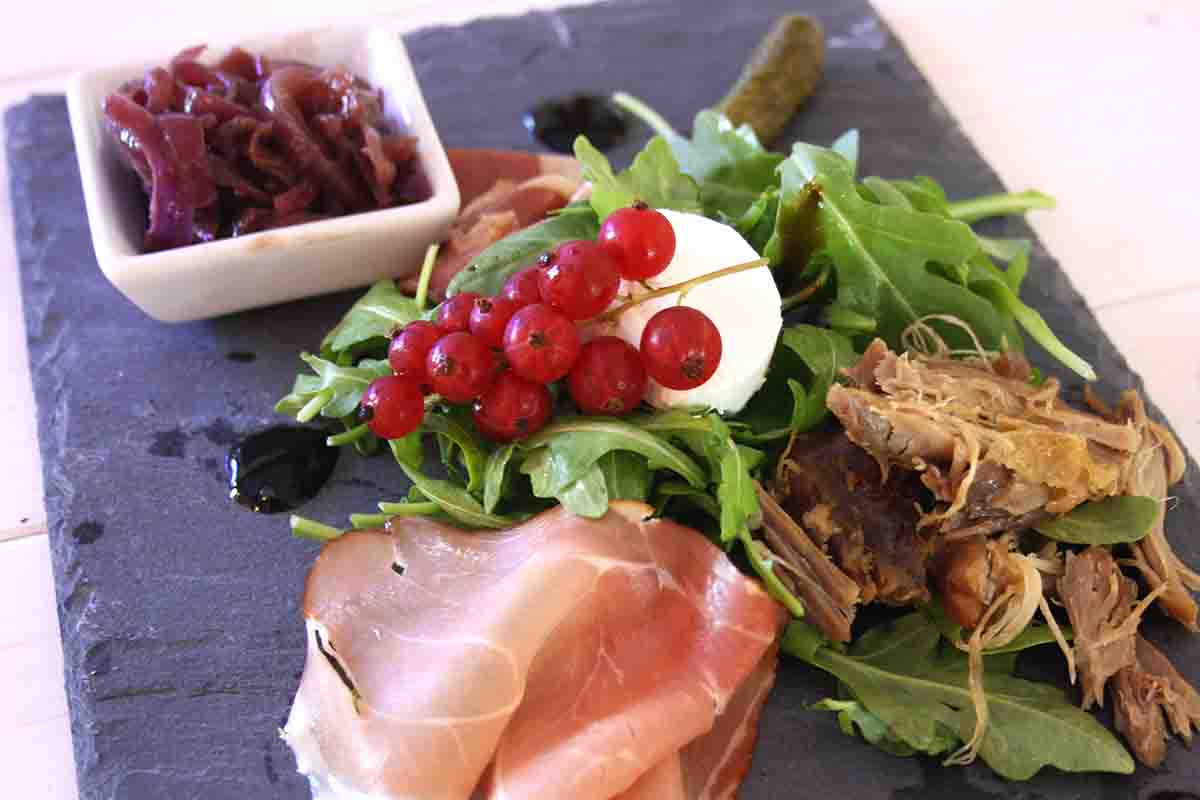 goat cheese, redcurrants, ham and shredded duck on a slate plate.