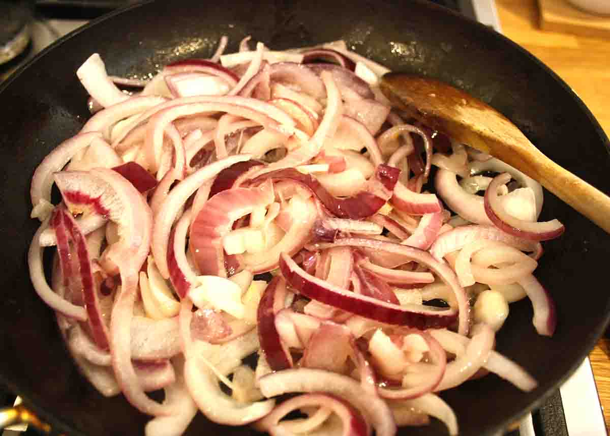 red onion slices in a frying pan.