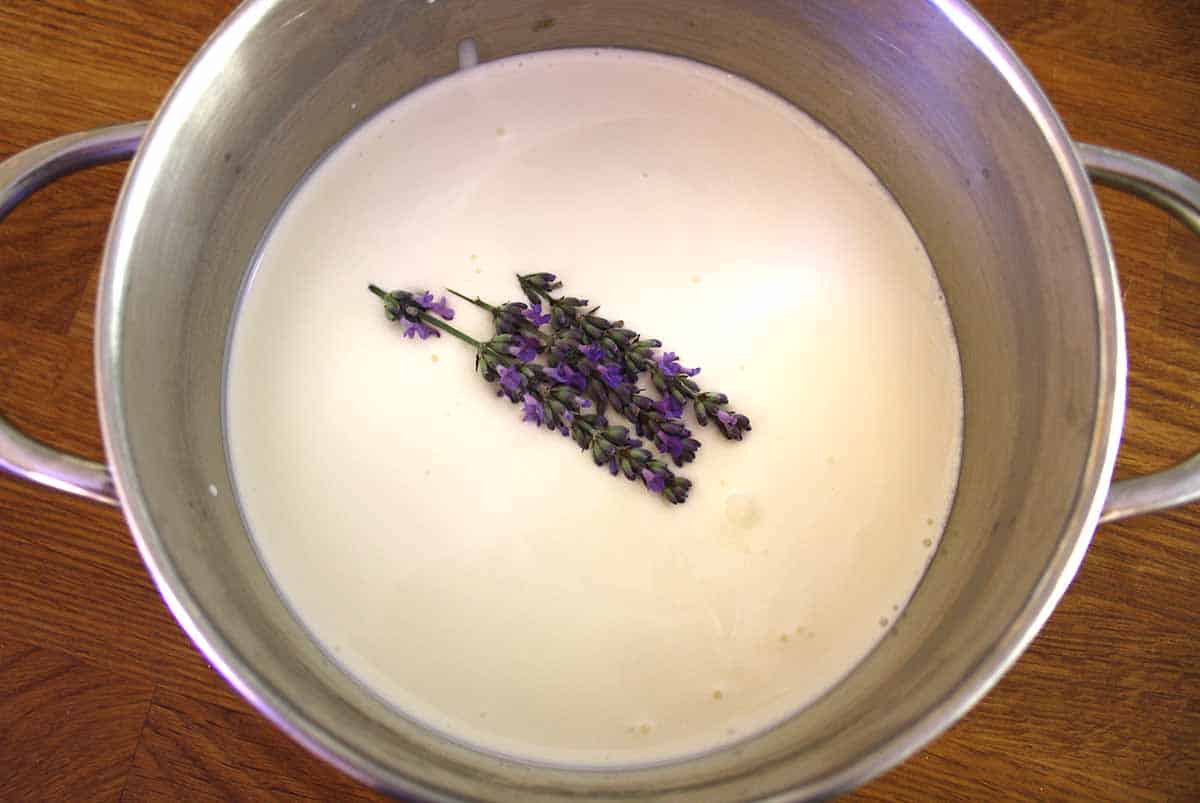 cream in a saucepan with a piece of lavender in it.