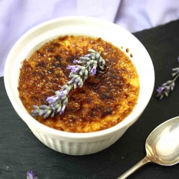 lavender creme brulee in a ramekin with a spoon on the side.