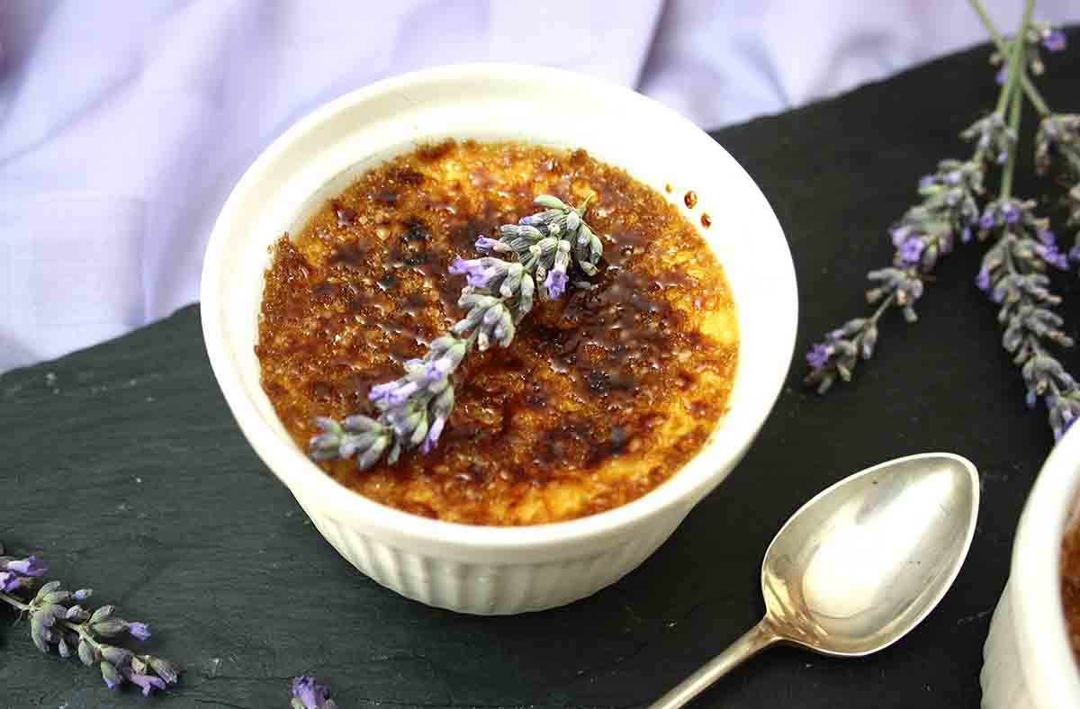lavender creme brulee in a ramekin with a spoon on the side.