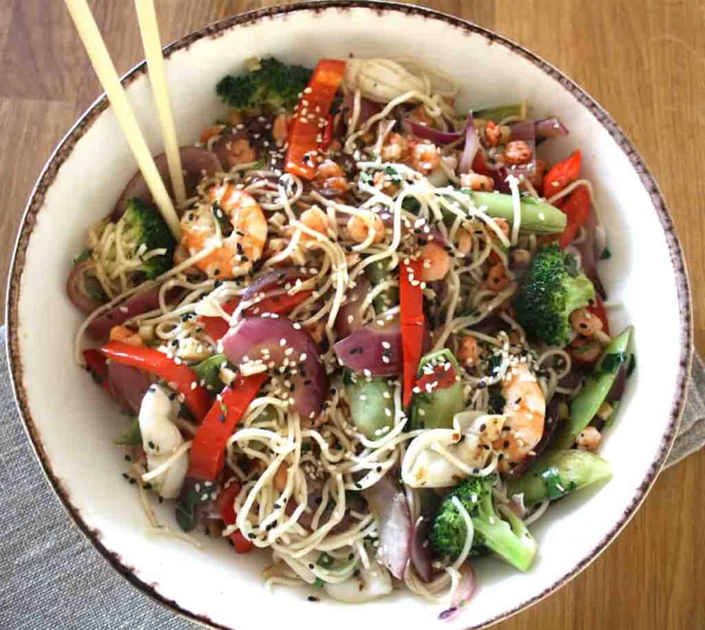 seafood chow mein in a large bowl with chop sticks.