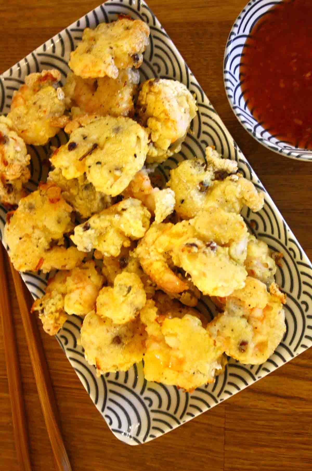 Sichuan prawns or Szechuan prawns on a plate with sauce in the background.