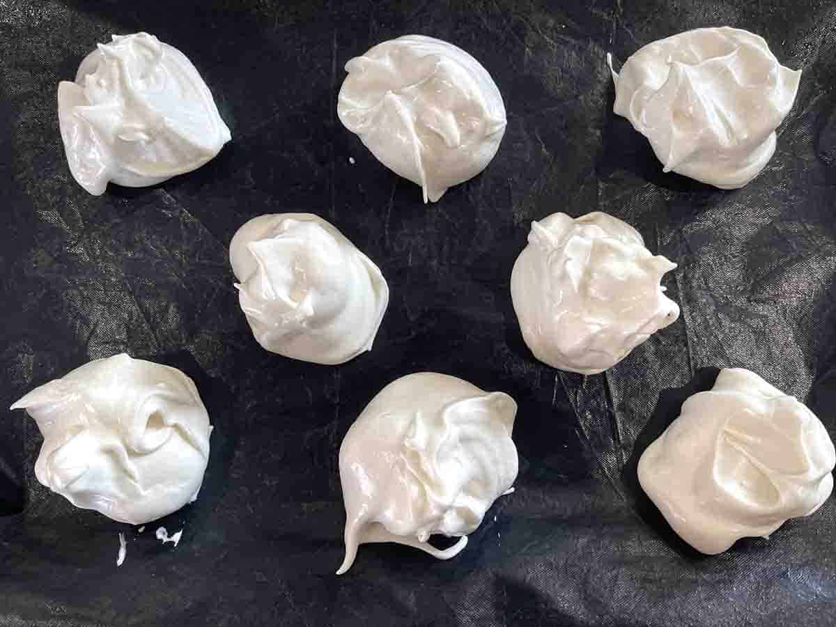 mounds of meringue on a tray ready to be baked. 