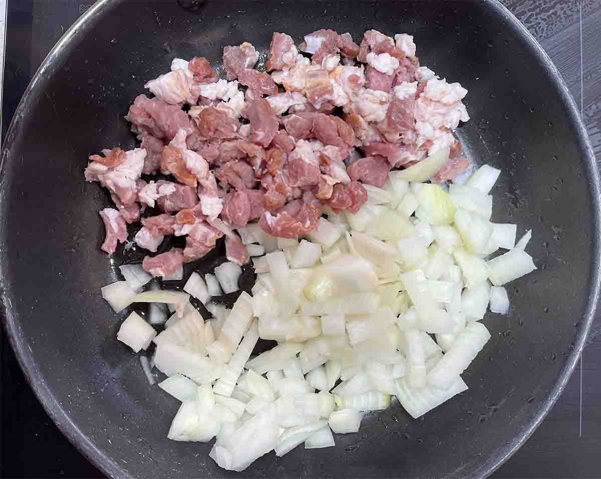 bacon and onion in a frying pan.