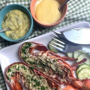 lobster on a plate with plain and dill mayonnaise in pots.