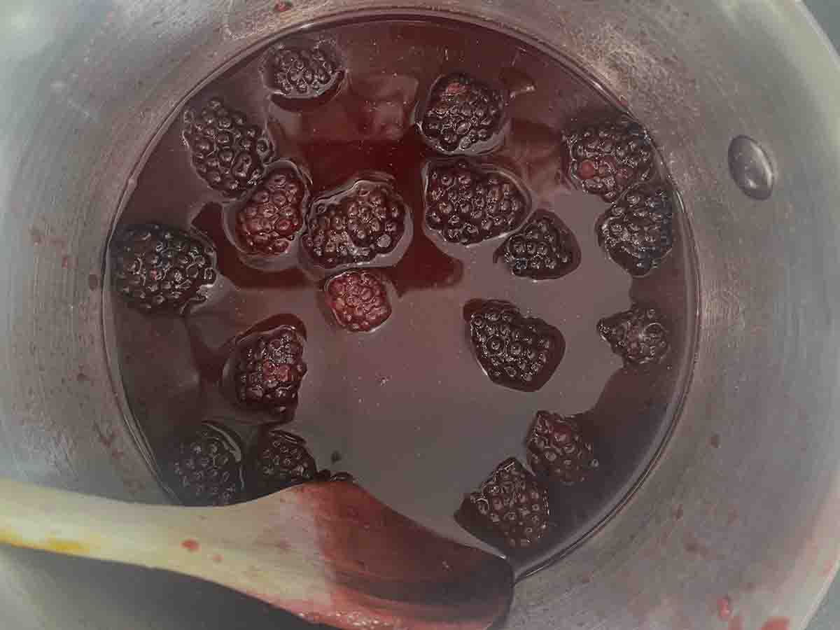 pureed clackberry sauce with whol raspberries added in a saucepan.